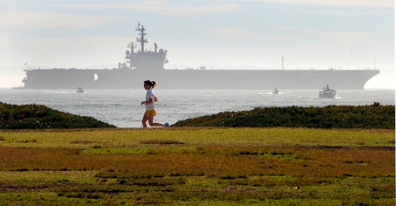 US Navy 080112-N-1722M-005 A jogger uses the bike path along Cabrillo Blvd. as the Nimitz-class nuclear-powered aircraft carrier USS Ronald Reagan (CVN 76), sits anchored offshore photo