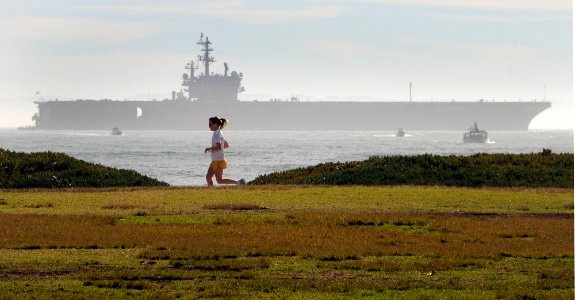 US Navy 080112-N-1722M-005 A jogger uses the bike path along Cabrillo Blvd. as the Nimitz-class nuclear-powered aircraft carrier USS Ronald Reagan (CVN 76), sits anchored offshore