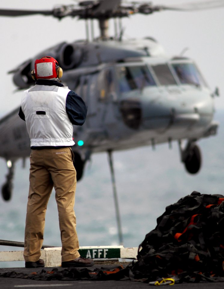 US Navy 080115-N-2984R-284 A crewmember assigned to the Nimitz-class nuclear powered aircraft carrier USS Harry S. Truman (CVN 75), observes an MH-60S Seahawk helicopter as it performs a vertical replenishment