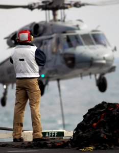 US Navy 080115-N-2984R-284 A crewmember assigned to the Nimitz-class nuclear powered aircraft carrier USS Harry S. Truman (CVN 75), observes an MH-60S Seahawk helicopter as it performs a vertical replenishment