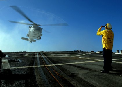US Navy 080127-N-7981E-047 Boatswain's Mate 1st Class William Geurin signals the SH-60F Seahawk carrying Secretary of the Navy (SECNAV) The Honorable Dr. Donald Winter to a landing aboard the Arleigh Burke-class guided-missile photo