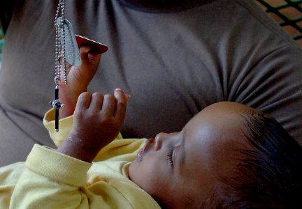 US Navy 080126-F-6318R-324 A baby at the Djibouti orphanage plays with the dog tags of a visiting service member photo