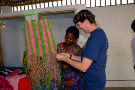 US Navy 080130-N-0193M-093 Mineman 1st class April Morehouse, an Africa Partnership Station (APS) volunteer assigned to the high speed vessel Swift (HSV 2) is taught how to weave a basket by a young girl at the Centre d' Accuei photo
