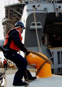US Navy 080124-N-6710M-005 Engineman 3rd Class Donald Jones releases a mooring line as the amphibious assault ship USS Essex (LHD 2) prepares to get underway from Sasebo, Japan