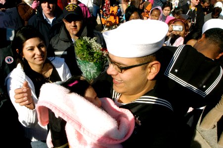 US Navy 080125-N-0486G-007 Culinary Specialist 2nd class Eber Varrazh hugs his newborn baby girl for the first time after he walked off the brow of The Guided-Missile Cruiser USS Vicksburg (CG 69)