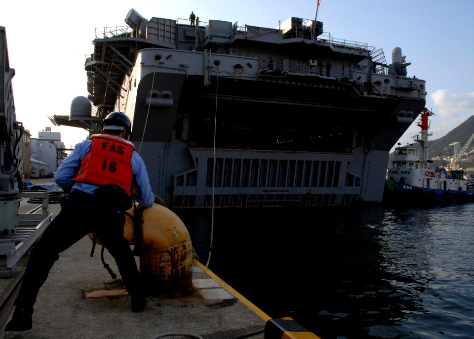 US Navy 080124-N-5067K-014 Electrician's Mate 2nd Class Justin Roy, assigned to the amphibious dock landing ship USS Tortuga (LSD 46), unties mooring lines for the amphibious assault ship USS Essex (LHD 2)