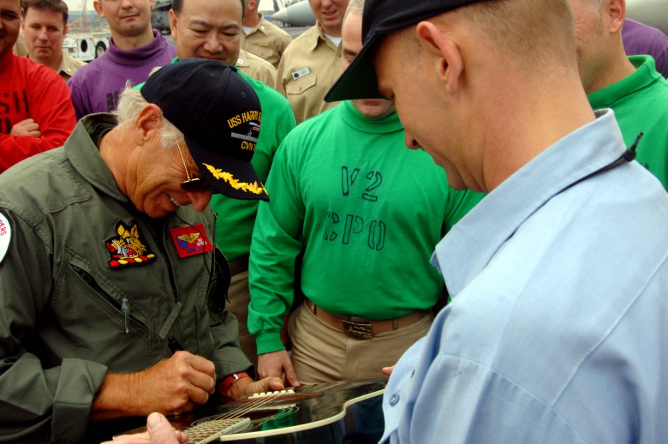 US Navy 080128-N-8923M-035 Recording artist Jimmy Buffett autographs a Sailor's guitar on the flight deck of the aircraft carrier USS Harry S. Truman (CVN 75) during a recent port visit in the Middle East