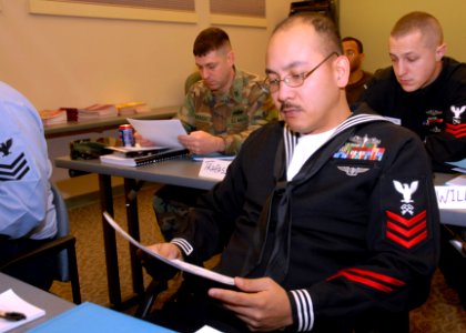 US Navy 080204-N-7656R-002 Storekeeper 1st Class Reiner Tomang, assigned to the Nimitz-class aircraft carrier USS John C. Stennis (CVN 74), studies military pay charts during a command financial specialist (CFS) class