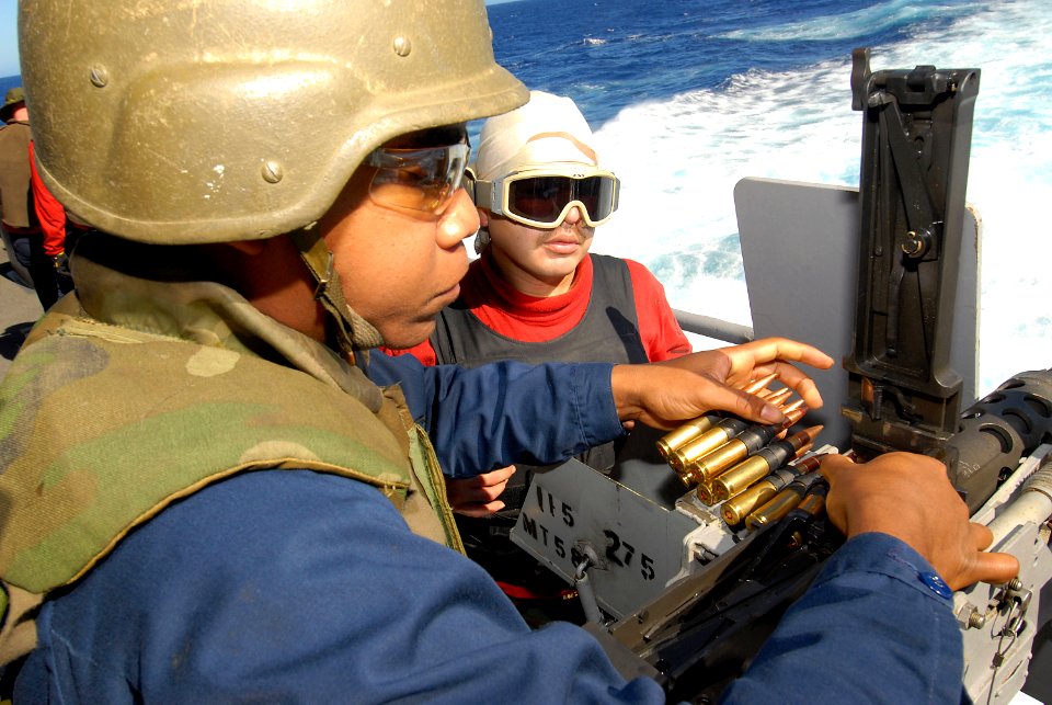 US Navy 080205-N-6326B-028 Gunner's Mate 2nd Class Rodolfo Jasso, right, teaches Aviation Ordnanceman Airman Travis Jackson how to load and fire a .50-caliber machine gun