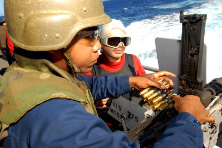 US Navy 080205-N-6326B-028 Gunner's Mate 2nd Class Rodolfo Jasso, right, teaches Aviation Ordnanceman Airman Travis Jackson how to load and fire a .50-caliber machine gun photo