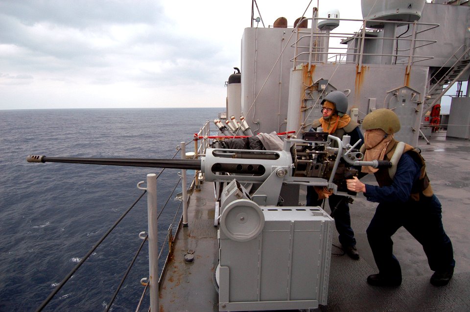 US Navy 080211-N-0807W-010 Seaman Albert J. Baugh, right, mans a 25-mm gun as Seaman Jacob P. Dieckmann reports to the bridge during a combat systems training environment drill aboard the dock landing ship USS Harpers Ferry (LS