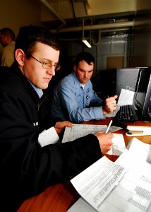 US Navy 080206-N-6538W-008 Electrician's Mate 2nd Class Nathan Hansen, left, helps Operations Specialist 1st Class Paul Lutton prepare his tax return aboard the Nimitz-class aircraft carrier USS John C. Stennis (CVN 74)