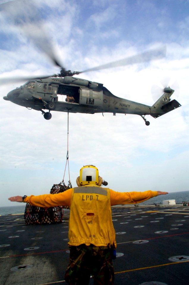 US Navy 080213-N-3925A-004 Aviation Boatswain's Mate (Handling) 3rd Class Gerson Gonzalez signals to an MH-60 helicopter during a vertical replenishment aboard the amphibious transport dock USS Cleveland (LPD 7)