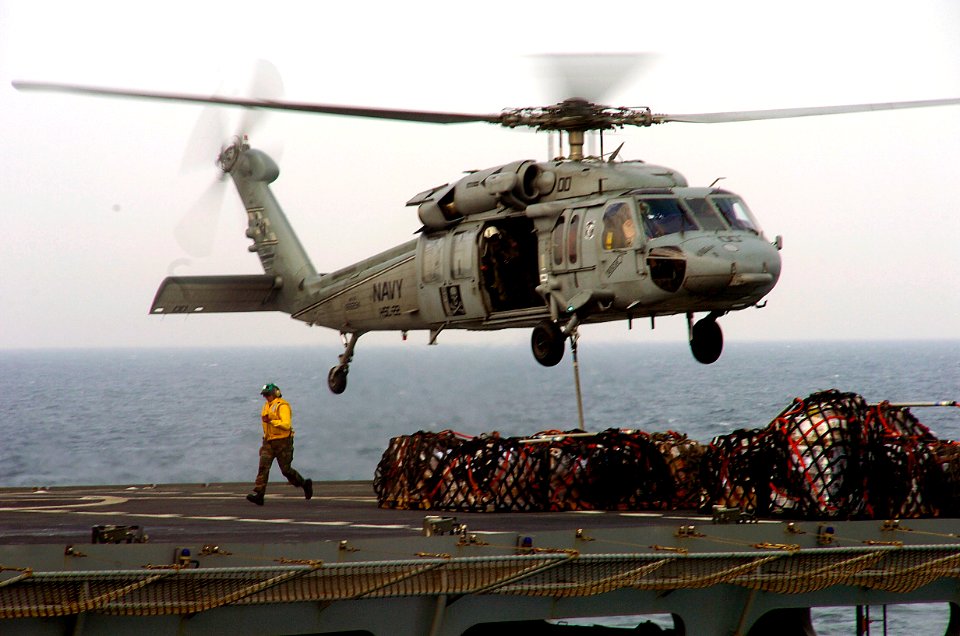 US Navy 080213-N-3925A-002 A sailor on the flight deck of the Military Sealift Command fast combat support ship USNS Arctic (T-AOE 8) gets out of the way after hooking cargo-laden pallets to an MH-60 helicopter during