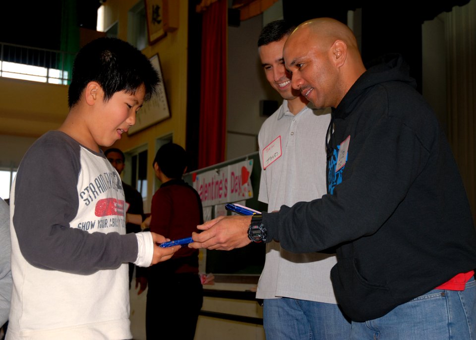 US Navy 080214-N-8547M-031 Chief Intelligence Specialist Greg Diaz and Religious Programs Specialist 3rd Class Cosme Rosete, both of Naval Mobile Construction Battalion (NMCB) 5, help students of Higa Elementary School learn En