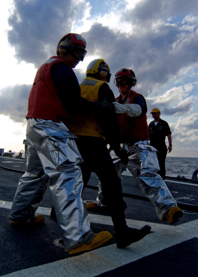 US Navy 080218-N-5253W-007 Damage Controlman 3rd Class Clifford Valasco and Gunner's Mate 3rd Class Joseph Frenz transport a victim from a simulated helicopter crash on the flight deck of the Arleigh Burke-class guided-missile