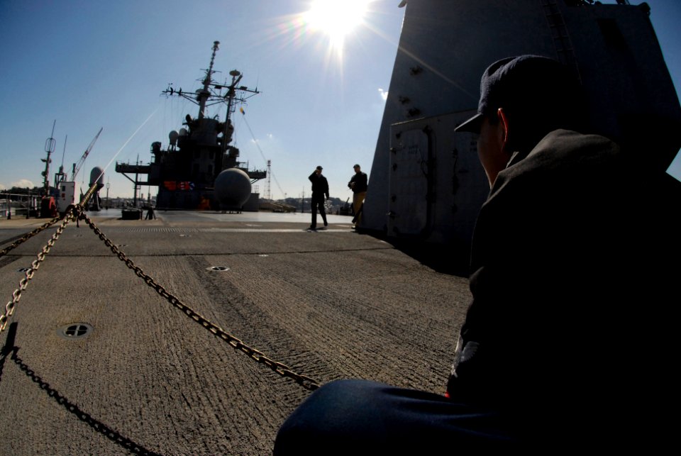 US Navy 080215-N-8546L-002 Electrician's Mate 2nd Class Thao Tran tightens down a securing line while his shipmates work aloft on the port side mast arm of the amphibious command ship USS Blue Ridge (LCC 19)