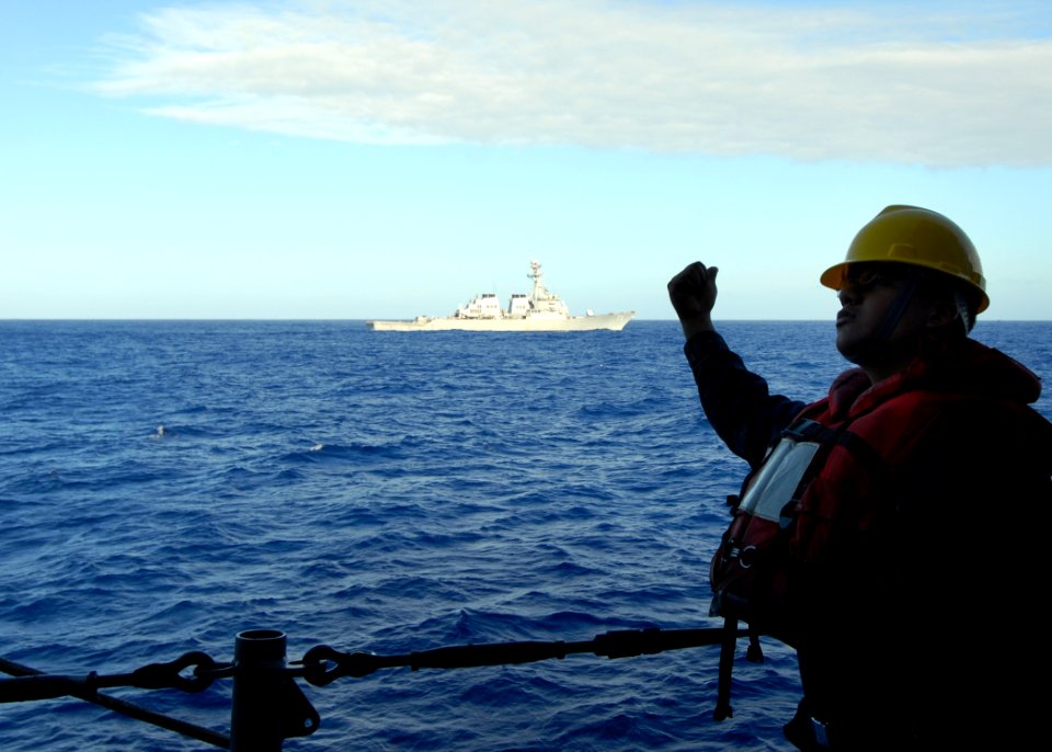 US Navy 080218-N-5476H-060 Boatswain's Mate 3rd Class Steven Leon signals the winch operator to boom out the rigid hull inflatable boat to be lowered into the water from the guided-missile cruiser USS Lake Erie (CG 70)
