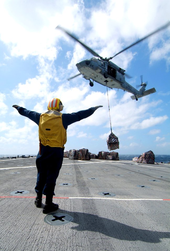 US Navy 080216-N-0807W-424 Boatswain's Mate 3rd Class Drew B. Leblanc, a landing signalman enlisted assigned to the dock landing ship USS Harpers Ferry (LSD 49), directs an MH-60S Seahawk