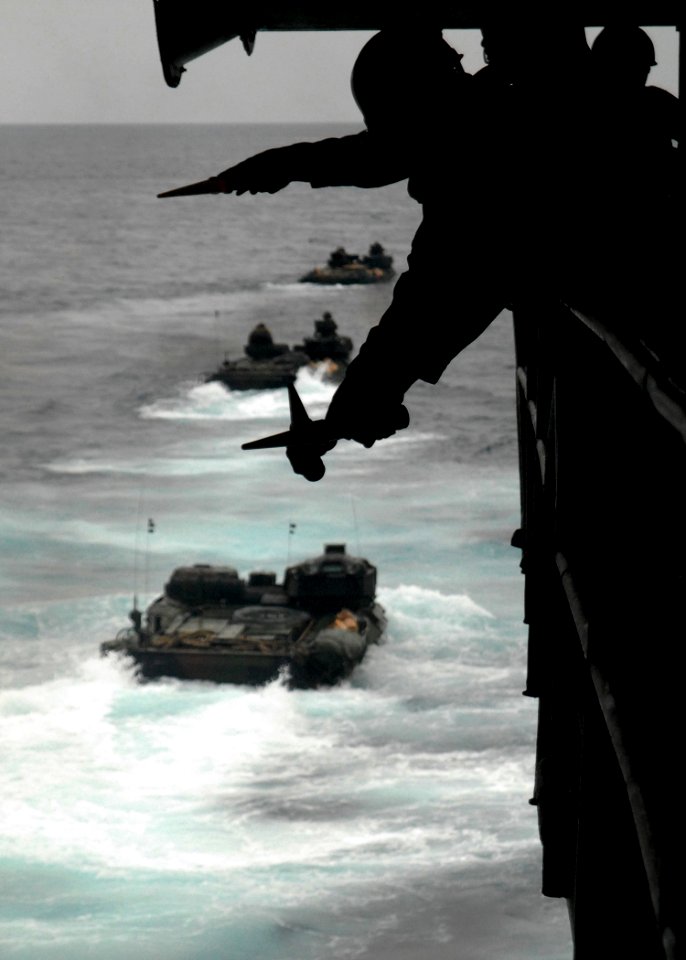 US Navy 080218-N-5067K-191 Seaman Keanne Q. Douglas crosses his wands to signal a Marine amphibious assault vehicle to hold position during a launch from the well deck of the amphibious transport dock USS Juneau (LPD 10)