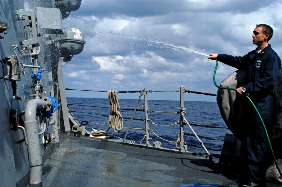 US Navy 080214-N-9123L-004 Operations Specialist 2nd Class Andrew Petrie uses a hose during a freshwater wash down of the guided-missile destroyer USS John S. McCain (DDG 56)