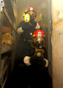 US Navy 080217-N-5476H-043 Damage Controlman 3rd Jason Gilberti operates a naval fire fighting thermal imager while Damage Controlman 3rd Class Duane Cunningham operates the fire hose nozzle during a damage control drill aboard