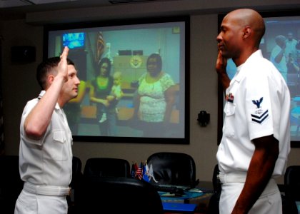 US Navy 080216-N-0803S-001 Lt. j.g. Ben Seward re-enlists Information Systems Technician 2nd Class Parvaris Washington while family and friends watch live via video teleconference from Texas