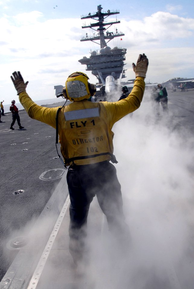 US Navy 080219-N-6326B-021 Aviation Boatswain's Mate (Handling) 3rd Class Jerell Hurdle directs an F-A-18F Super Hornet to a catapult during flight operations aboard the aircraft carrier USS Nimitz (CVN 68)