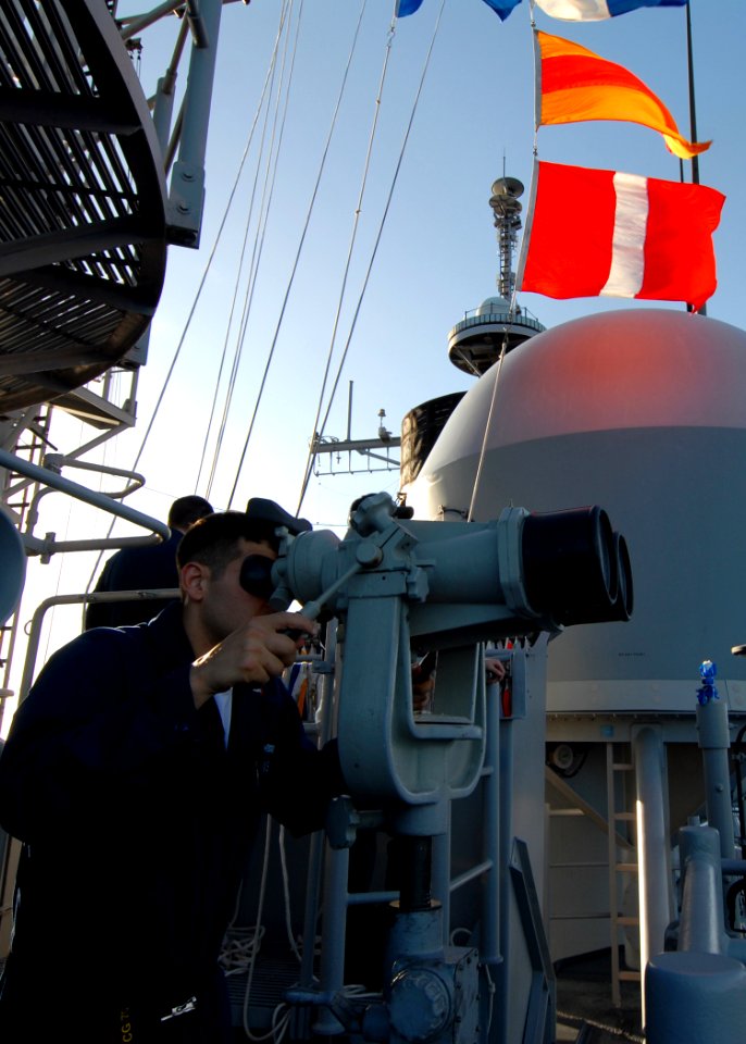 US Navy 080218-N-5476H-116 Quartermaster 3rd Class Ronald Masulis, of Danville, Ill., looks through ship mounted binoculars on the signal bridge in order to read flag signals from the guided-missile destroyer USS Decatur (DDG 7