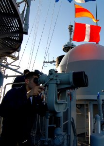 US Navy 080218-N-5476H-116 Quartermaster 3rd Class Ronald Masulis, of Danville, Ill., looks through ship mounted binoculars on the signal bridge in order to read flag signals from the guided-missile destroyer USS Decatur (DDG 7