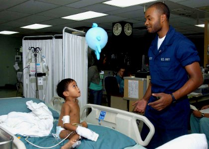 US Navy 080607-N-0209M-007 Three-year-old Jose Angelo Dacuycuy and Hospital Corpsman Daniel Garrett play with a balloon after Dacuycuy received surgery to correct his Hirschsprung's disease