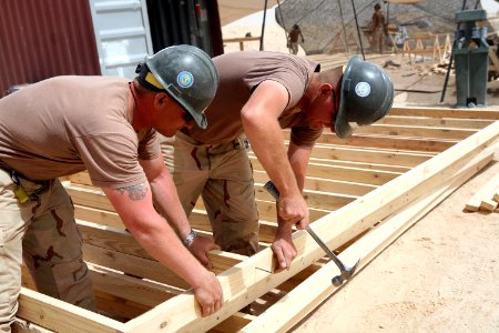 US Navy 080606-N-9623R-016 Utilitiesman 1st Class Todd Feltus, left, and Builder 1st Class Jeffrey Hood work to construct floors and trusses for South West Asian huts photo