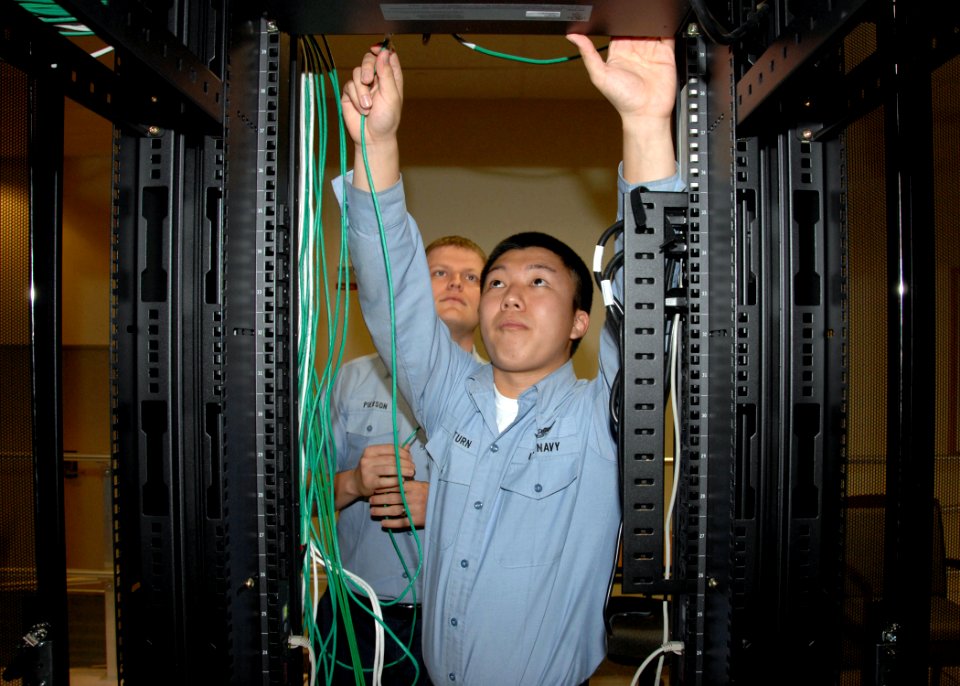 US Navy 080528-N-2147L-004 Information Technician 2nd Class Darrell Pierson observes as Information Technician Seng Saeturn reconfigures network cable on the Navy Cyber Defense Operations Command network