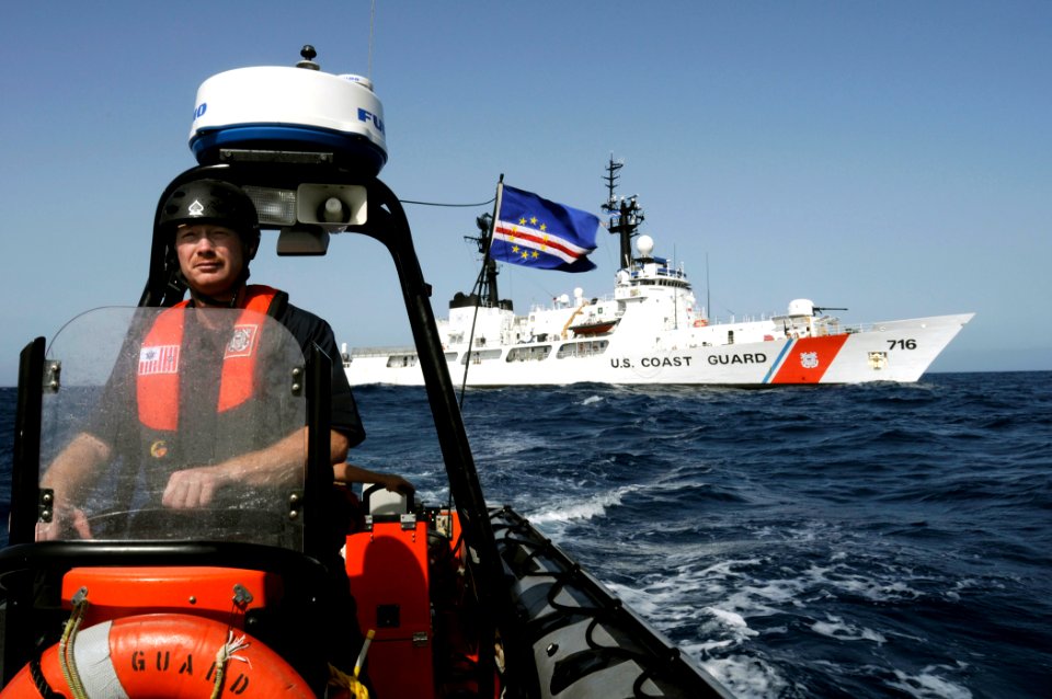 US Navy 080609-G-2443T-001 U. S. Coast Guard Chief Boatswain's Mate James Moerls steers an over-the-horizon small boat from the U.S. Coast Guard Cutter Dallas, in background, to conduct a multi-national vessel boarding