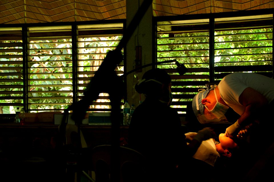 US Navy 080611-N-7498L-242 Lt. Cmdr. Ron Citro, a dentist embarked aboard the Military Sealift Command hospital ship USNS Mercy (T-AH 19), performs a tooth extraction on a patient in an improvised dental office photo