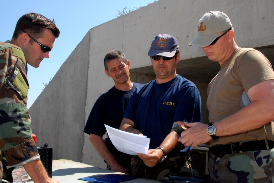 US Navy 080611-N-3289C-174 Spanish Sargento Primero Manuel Gutierrez Ramirez, assigned to the Spanish Navy's Unidad Especial Desactivad De Explosivo (U.E.D.E), talks with Lt. Matthew Coombs and Chief Explosive Ordnance Disposal