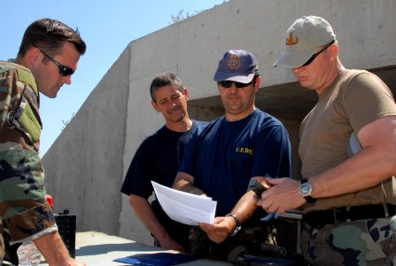 US Navy 080611-N-3289C-174 Spanish Sargento Primero Manuel Gutierrez Ramirez, assigned to the Spanish Navy's Unidad Especial Desactivad De Explosivo (U.E.D.E), talks with Lt. Matthew Coombs and Chief Explosive Ordnance Disposal
