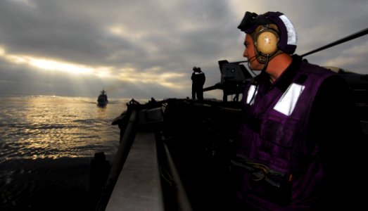 US Navy 080613-N-6538W-063 Aviation Boatswain's Mate Airman Joshua Hube watches as the guided-missile cruiser USS Lake Champlain (CG 57) makes its approach along side the Nimitz-class aircraft carrier USS John C. Stennis (CVN 7