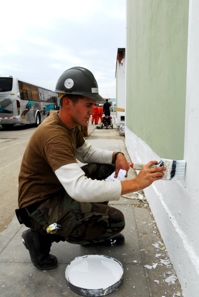 US Navy 080614-N-6410J-043 Utilitiesman 3rd Class Jeffrey Schuett, assigned to Navy Mobile Construction Battalion (NMCB) 5 embarked aboard the amphibious assault ship USS Boxer (LHD 4), paints the trim on a building