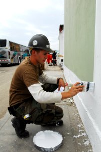 US Navy 080614-N-6410J-043 Utilitiesman 3rd Class Jeffrey Schuett, assigned to Navy Mobile Construction Battalion (NMCB) 5 embarked aboard the amphibious assault ship USS Boxer (LHD 4), paints the trim on a building