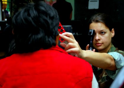 US Navy 080612-A-0348M-002 Lt. Megan Rieman, embarked aboard the amphibious assault ship USS Boxer (LHD 4), examines a patient's eyes at the Huacho Salon Parochial medical site during Continuing Promise 2008 photo