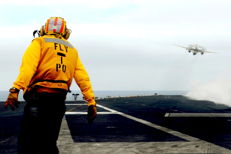 US Navy 080614-N-0684R-086 Aviation Boatswain's Mate (Handling) Edison Grace turns to watch an E-2C Hawkeye assigned to the