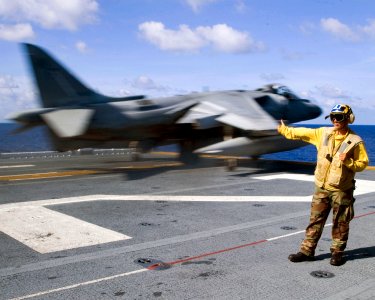 US Navy 080619-N-0483B-009 Aviation Boatswain's Mate 3rd Class Mark R. Joseph signals to an AV-8B Harrier assigned to