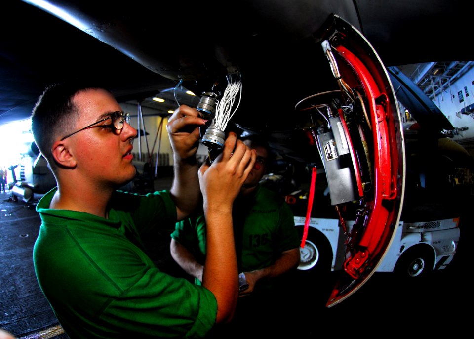 US Navy 080617-N-2638R-001 Aviation Electronics Technician 2nd Class Craig Christensen,left, of Minden, Nev., splices wires together on an EA-6B Prowler assigned to Electronic Attack Squadron (VAQ) 136