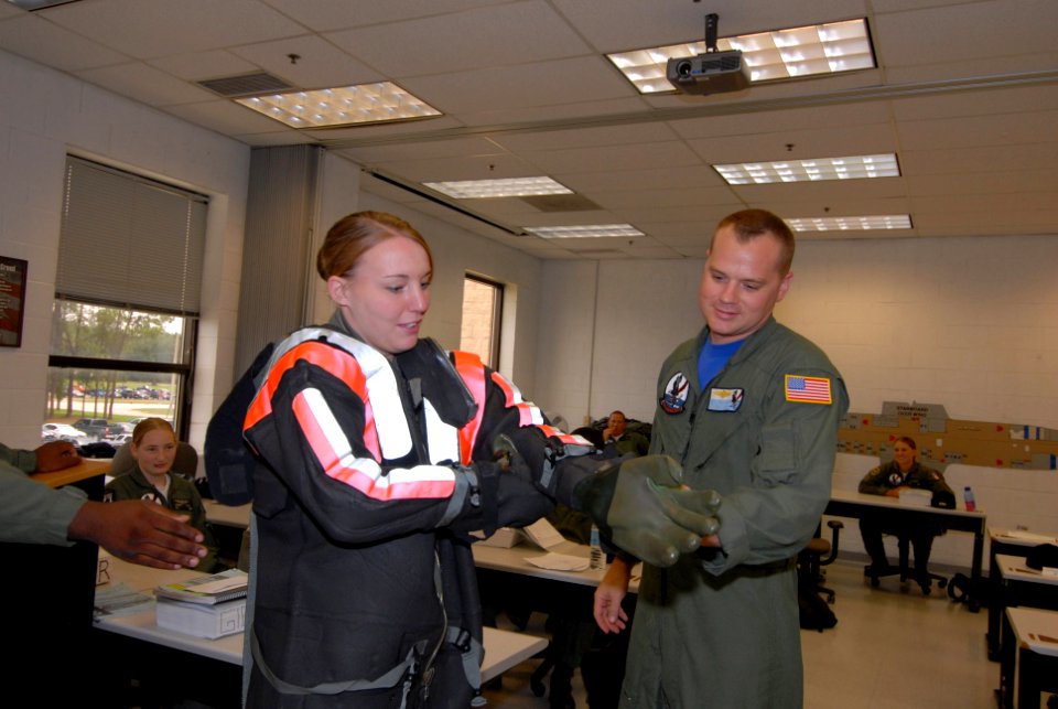 US Navy 080612-N-8102J-113 Aviation Warfare Systems Operator Airman Apprentice Jessica Deaver demonstrates how to properly don an anti-exposure suit with the assistance of Aviation Warfare Systems Operator 1st Class Jeremy Aule