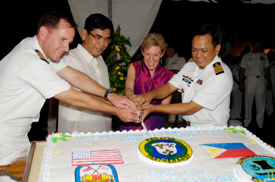 US Navy 080617-N-0209M-005 Capt. William A. Kearns, Edsel T. Custodio, Kristie A. Kenney and Capt. Crispin P. Mercado cut a cake together during a reception ceremony aboard Mercy