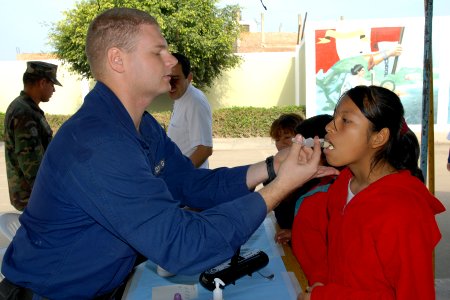 US Navy 080615-N-6410J-034 Coast Guard Health Services Technician 3rd Class Jason Labenne, embarked aboard the amphibious assault ship USS Boxer (LHD 4), gives a young girl an immunization photo