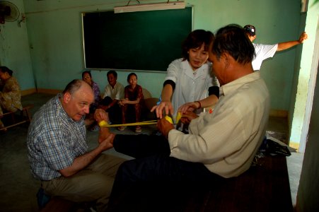 US Navy 080620-N-7498L-160 Lt. Cmdr. Daniel Gage, left, a physical therapist, and Vietnamese physician Nguyen Thi Hai Yen help a patient perform exercises using a rubber ribbon to alleviate arthritis in his ankle