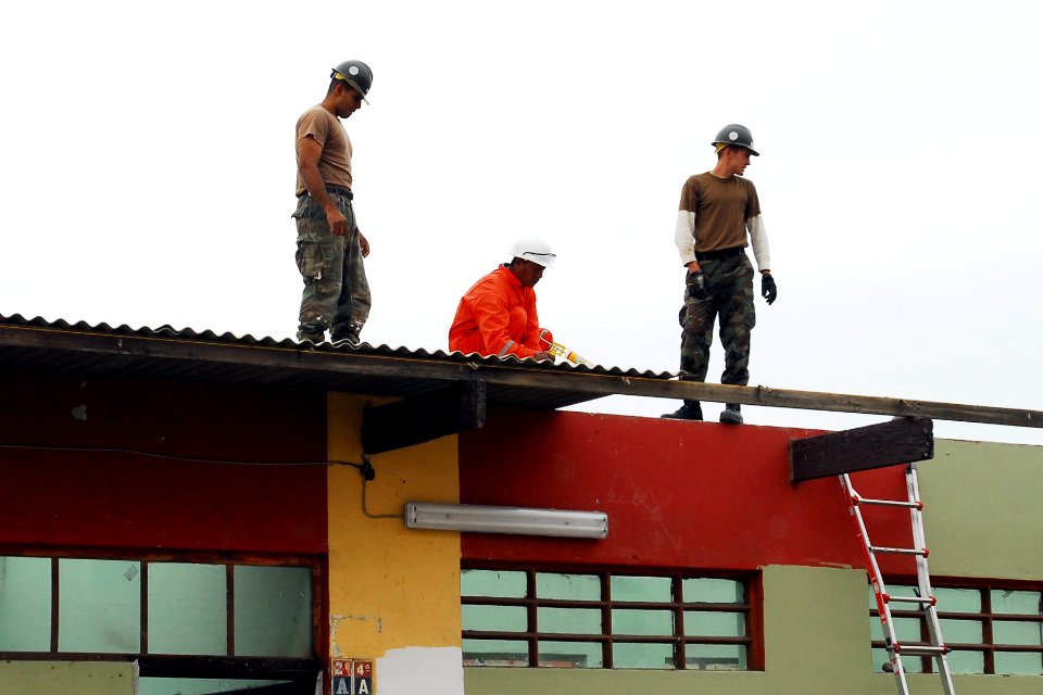 US Navy 080614-N-6410J-026 Seabees assigned to Construction Battalion Maintenance Unit (CBMU) 303 embarked aboard the amphibious assault ship USS Boxer (LHD 4), work with a Peruvian construction worker to replace the roof on a