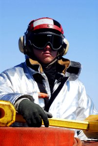 US Navy 080620-N-2610F-001 Aviation Boatswain's Mate Airman Patrick Dent observes flight operations while standing in a crash and salvage hot-suit-man watch on the flight deck aboard the Nimitz-class aircraft carrier USS John C